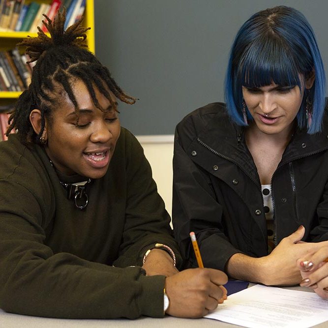 Two non-binary students doing work together in class